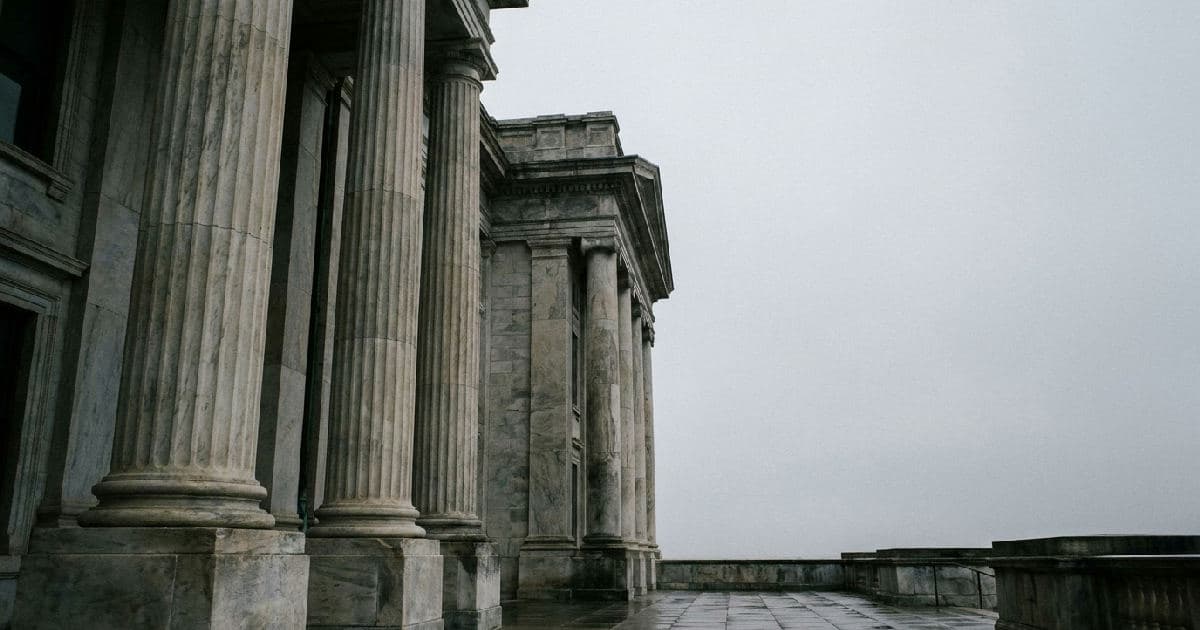 Classical marble columns of a government building beneath an overcast sky.